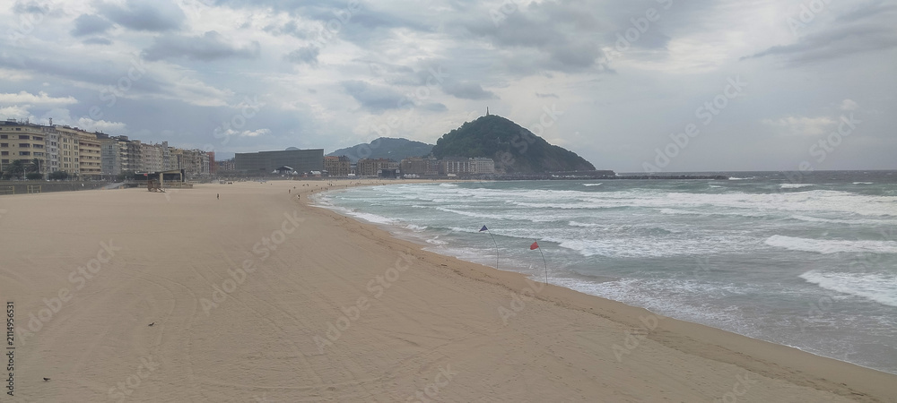 Fototapeta premium Vista general de la costa y la ciudad bajo cielo nublado en San Sebastián, España