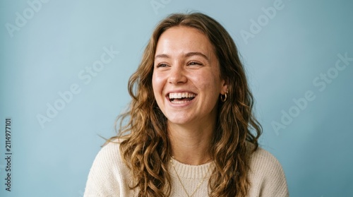 A woman with long, wavy hair smiling against a blue background.