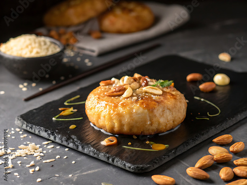 A single Mawa Kachori, crisp golden pastry filled with rich khoya and nuts, lightly glazed with sugar syrup, black slate plate, luxurious fine dining presentation, dramatic lighting