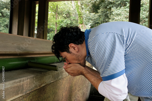 Man Purifying at Japanese Shrine Fountain
