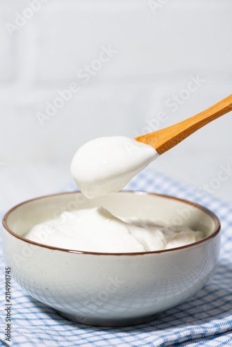 thick greek yogurt in a bowl and a spoon with yogurt, vertical