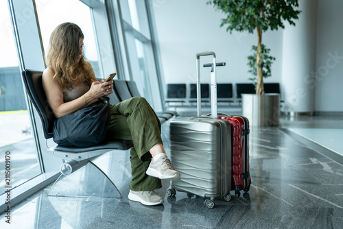 Wide angle view of traveler seated at airport gate with luggage and large glass windows emphasizing peaceful departure experience and contemporary architecture