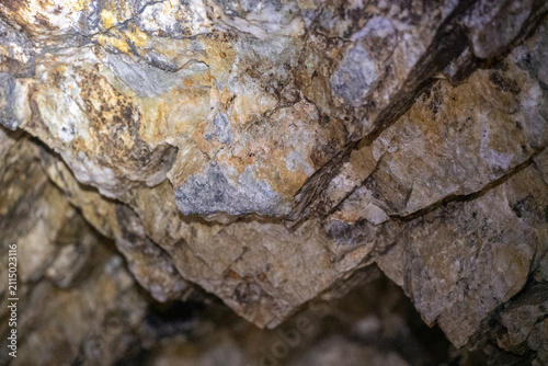 Fotografie Exploration de l'intérieur d'une mine désaffectée du Mont Chemin en Valais, silhouette d'un explorateur près de la lumière naturelle au bout du tunnel rocheux