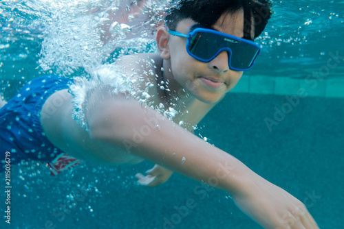 Quadro su tela Underwater shoot of a boy swimming while wearing American flag shorts on 4th of