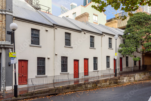 Old terraced house along a street in a historic district after an autumnal thunderstorm. A rainbow is visible across the sky.
