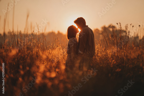 Romantic couple kissing in a field at sunset