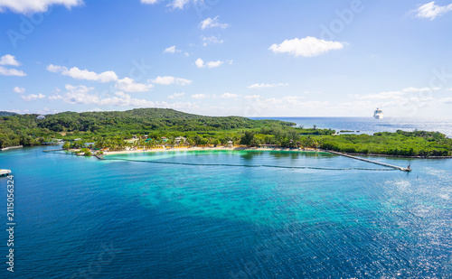 View of Mahogany Bay beach with ship sailing to port. 