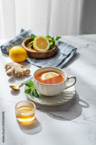 Cup of tea with lemon, ginger and mint on a marble background with honey