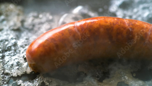 Fotografía Juicy pork sausage sizzling in bubbling hot water or oil cooking for delicious meal preparation