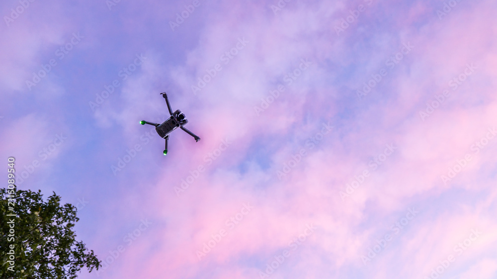 Naklejka premium Modern drone flying high in the colorful twilight sky with soft clouds