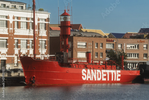 Foto A bright red lightship named Sandettie sits along the Dunkirk waterfront, its lantern tower rising beside the surrounding harbor buildings
