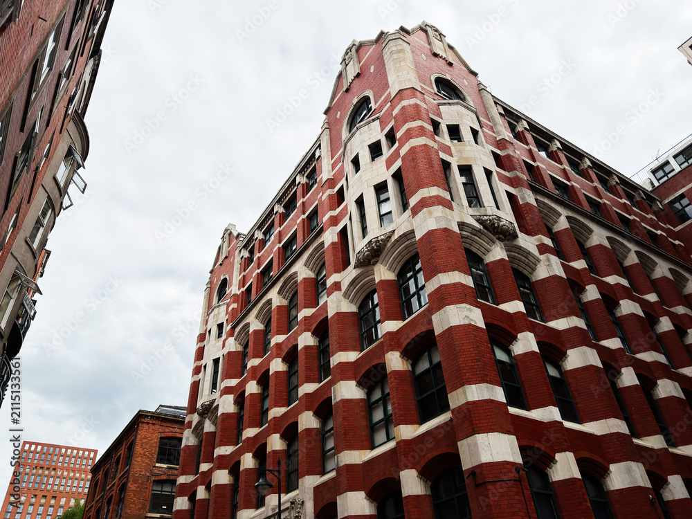 Obraz premium Historic red brick architecture and ornate commercial building in Manchester, UK captured from dramatic low angle perspective