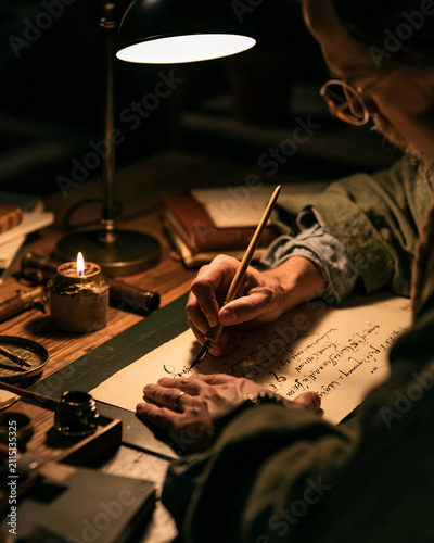 Vintage desk workspace with hand writing by candlelight, ink pen and paper for creative inspiration and reflection