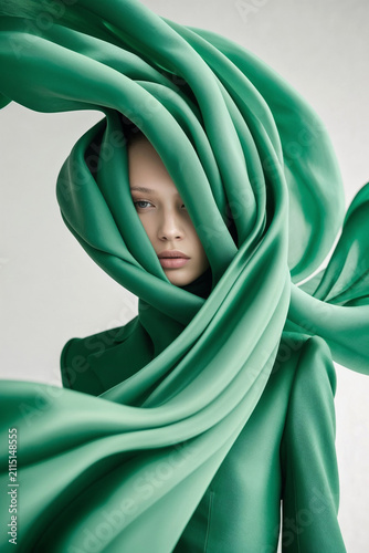 fashion portrait of young woman enveloped in flowing green fabric