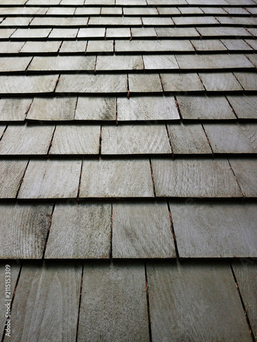 Texture of weathered wooden shingles in silvery-gray tones. Rustic cladding background. Rustic roofs and facades. Architecture and construction.