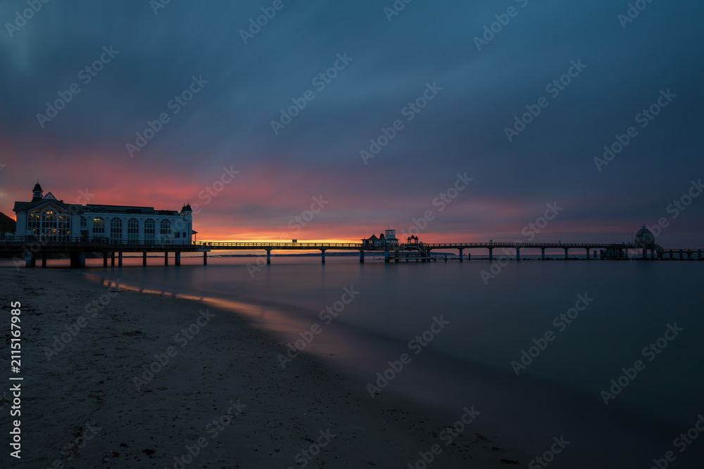 Fototapeta premium Wide angle view of Sellin pier extending into tranquil ocean during dark twilight
