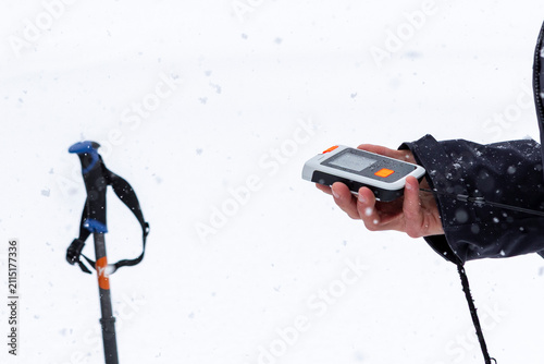 Hand holding avalanche transceiver in snowy ski touring