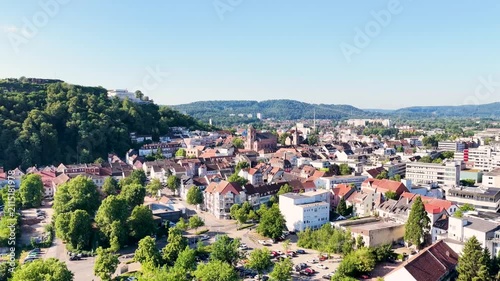 Malerische Ansicht von Homburg an der Saar mit der markanten Stadtkirche, dichten grünen Bäumen im Vordergrund und dem bewaldeten Schlossberg unter blauem Sommerhimmel.