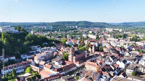 Malerische Ansicht von Homburg an der Saar mit der markanten Stadtkirche, dichten grünen Bäumen im Vordergrund und dem bewaldeten Schlossberg unter blauem Sommerhimmel.