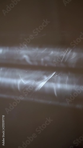 Abstract white smoke swirl rising against a dark blurred background.	