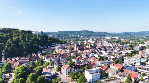 Malerische Ansicht von Homburg an der Saar mit der markanten Stadtkirche, dichten grünen Bäumen im Vordergrund und dem bewaldeten Schlossberg unter blauem Sommerhimmel.