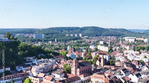 Malerische Ansicht von Homburg an der Saar mit der markanten Stadtkirche, dichten grünen Bäumen im Vordergrund und dem bewaldeten Schlossberg unter blauem Sommerhimmel.
