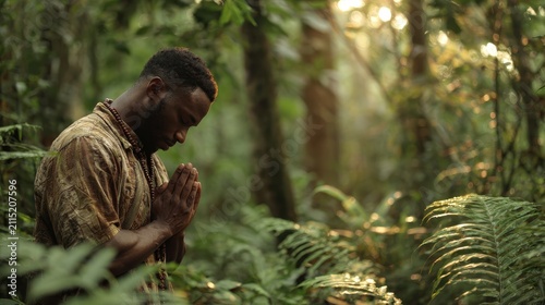 African man in prayer amid lush greenery: serene outdoor portrait in a forest setting