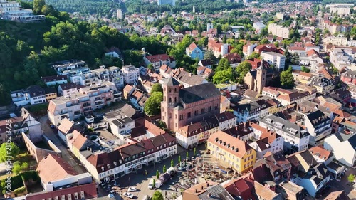 Malerische Ansicht von Homburg an der Saar mit der markanten Stadtkirche, dichten grünen Bäumen im Vordergrund und dem bewaldeten Schlossberg unter blauem Sommerhimmel.