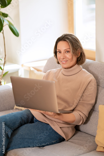Smiling middle aged female sitting with laptop