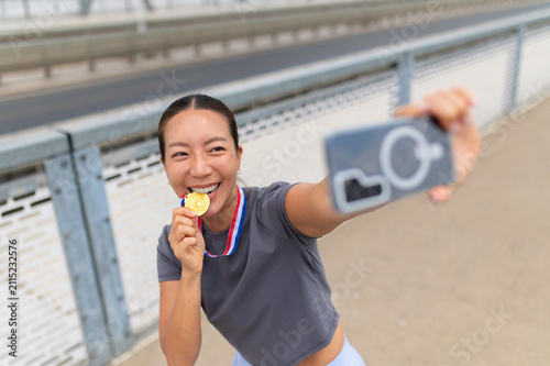 Woman celebrating victory biting gold medal taking selfie