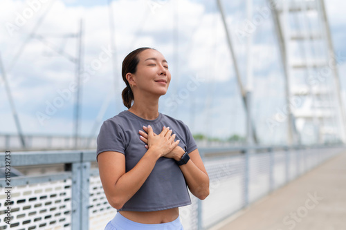 Quadro su tela Woman practicing mindful breathing and gratitude outdoors on bridge