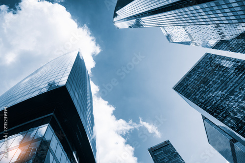 Photography Tall glass skyscrapers of business offices in city reflect blue sky, clouds, and other skyscrapers