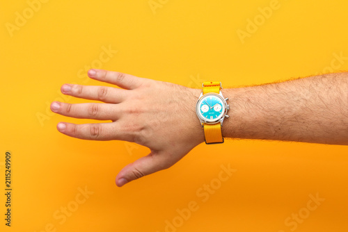 Photography A man hand wearing a stylish wristwatch with a bright turquoise dial and yellow
