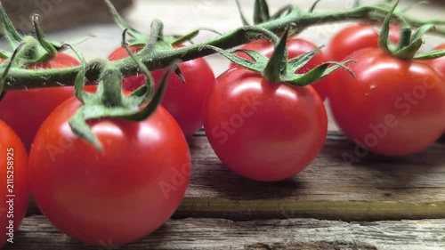 Closeup branch with ripe cherry tomatoes on dark wooden table