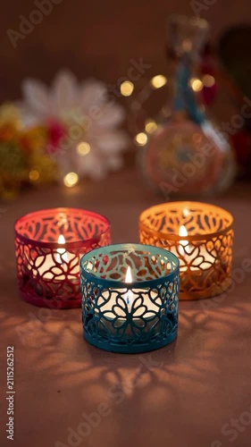 Three colorful decorative metal tea light holders lit for Diwali
