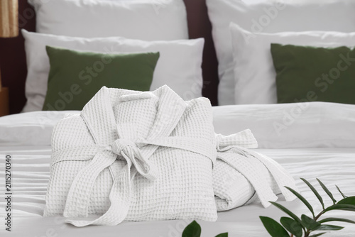 Folded bathrobes on bed in ...