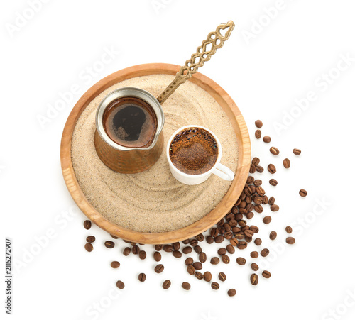 Foto Cezve and cup of hot turkish coffee on sand against white background