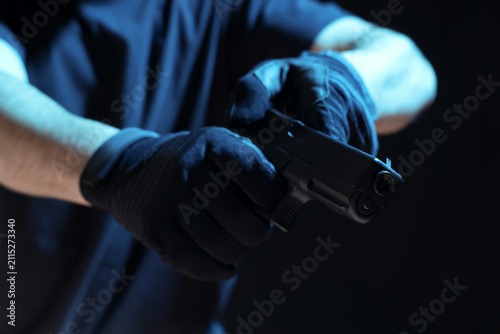 Obraz na płótnie Man with gun reloading on black background, closeup