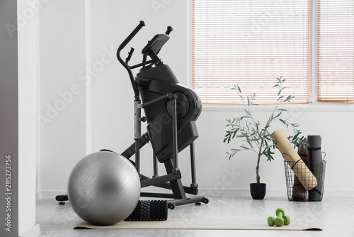 Interior of modern gym with bicycle machine, fitness ball, yoga mats and spor...