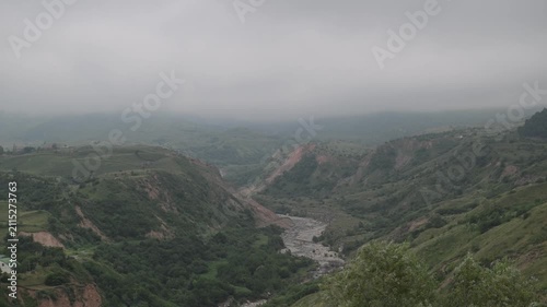 A mountain landscape with a beautiful mountain stream and a forest in the fog