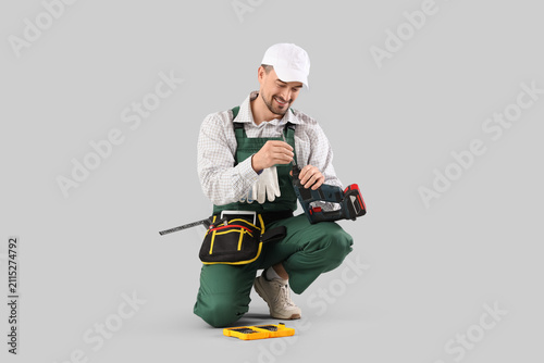Male technician with drill on light background