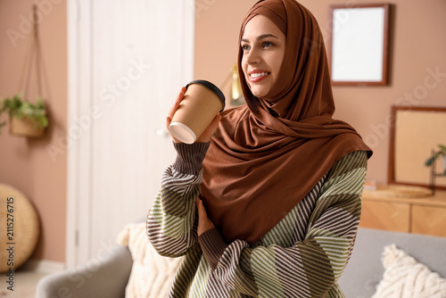Young Muslim woman with cup...