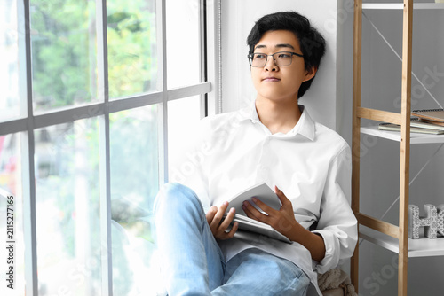 Young Asian man reading boo...