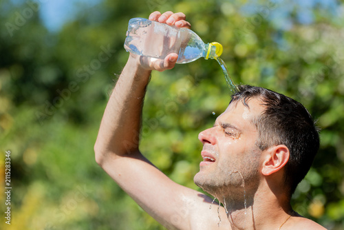 Bild auf Leinwand young man splashing himself with water during a summer heat wave
