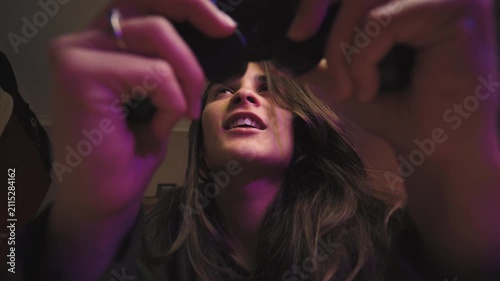 Low-angle shot of a young Hispanic woman playing video games in her bedroom, celebrating an exciting victory. Gaming, fun, success, home entertainment, authentic lifestyle.
