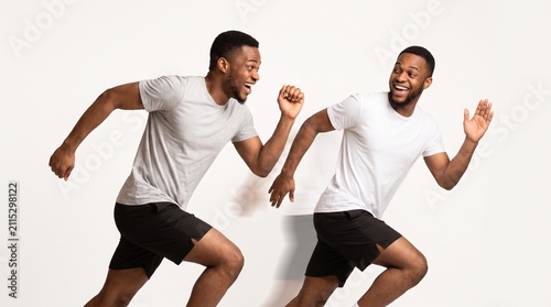 Two happy men running side by side in athletic wear on a white background