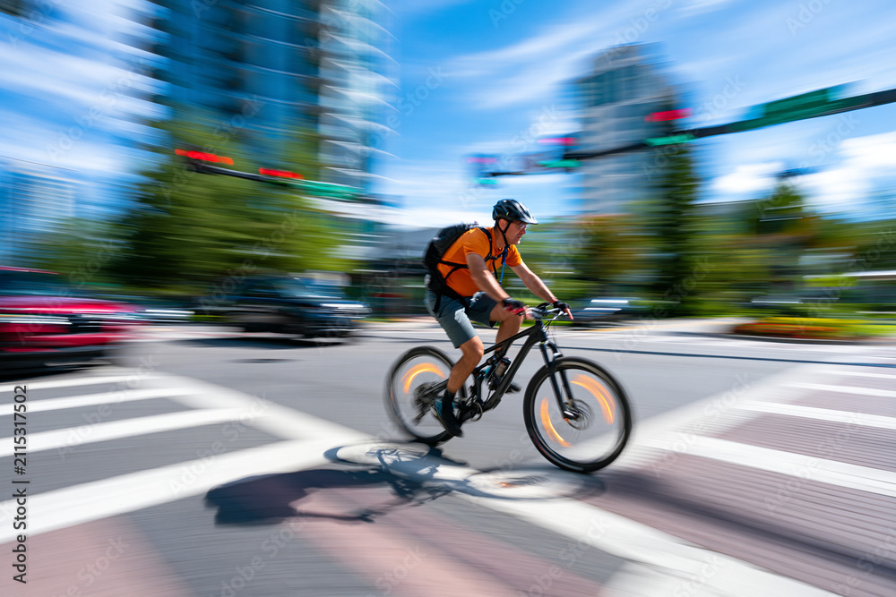 Fototapeta premium Commuter cycling through a summer city intersection
