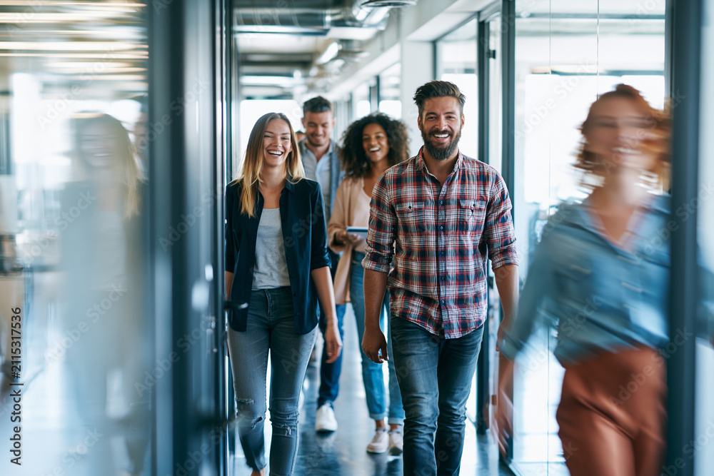 Obraz premium Coworkers laughing while walking a sunlit office hallway