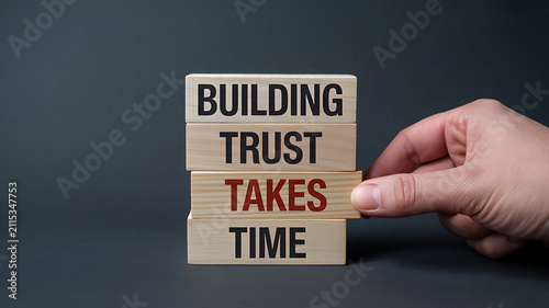 Building trust takes time written on wooden blocks with a hand adjusting the word takes Keywords