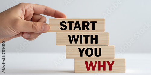 Hand arranging wooden blocks in a stair-like formation spelling STARTWITHYOUWHY